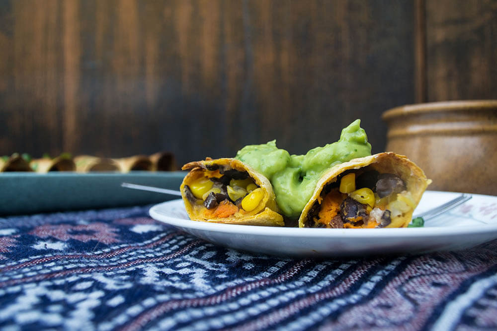 Two soft tacos filled with black beans, sweet potato, avocado, and cilantro