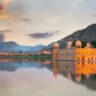 Jal Mahal in Jaipur, Rajasthan, reflected in Man Sagar Lake during sunset with Aravalli hills in the background.
